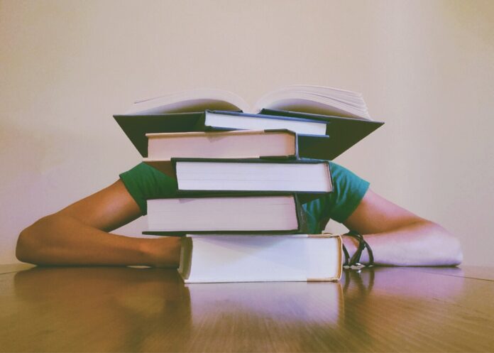 a person lies slumped behind a pile of books
