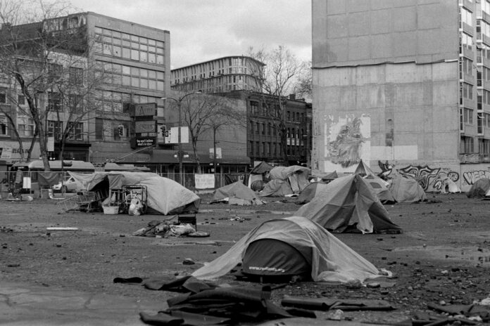 This image is of the downtown east side in Vancouver. Multiple tents can be seen in the middle of an abandoned lot.