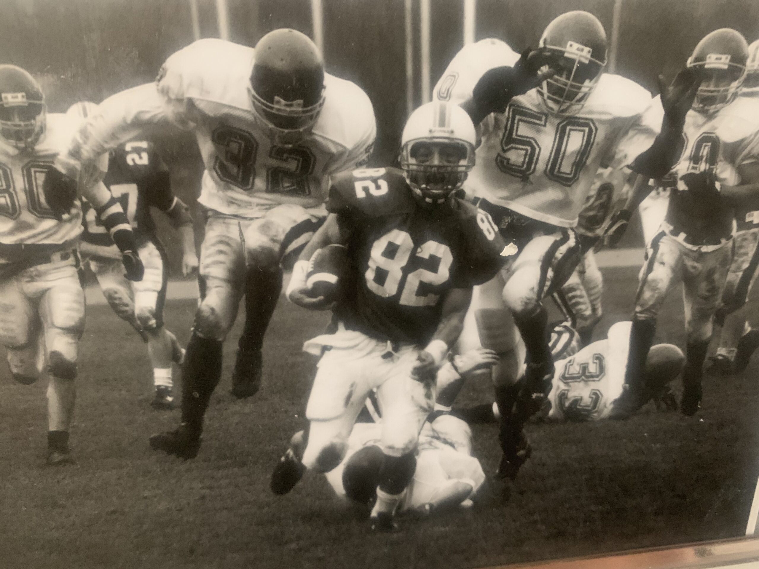 A black and white photo of Jon Choboter running with the ball.