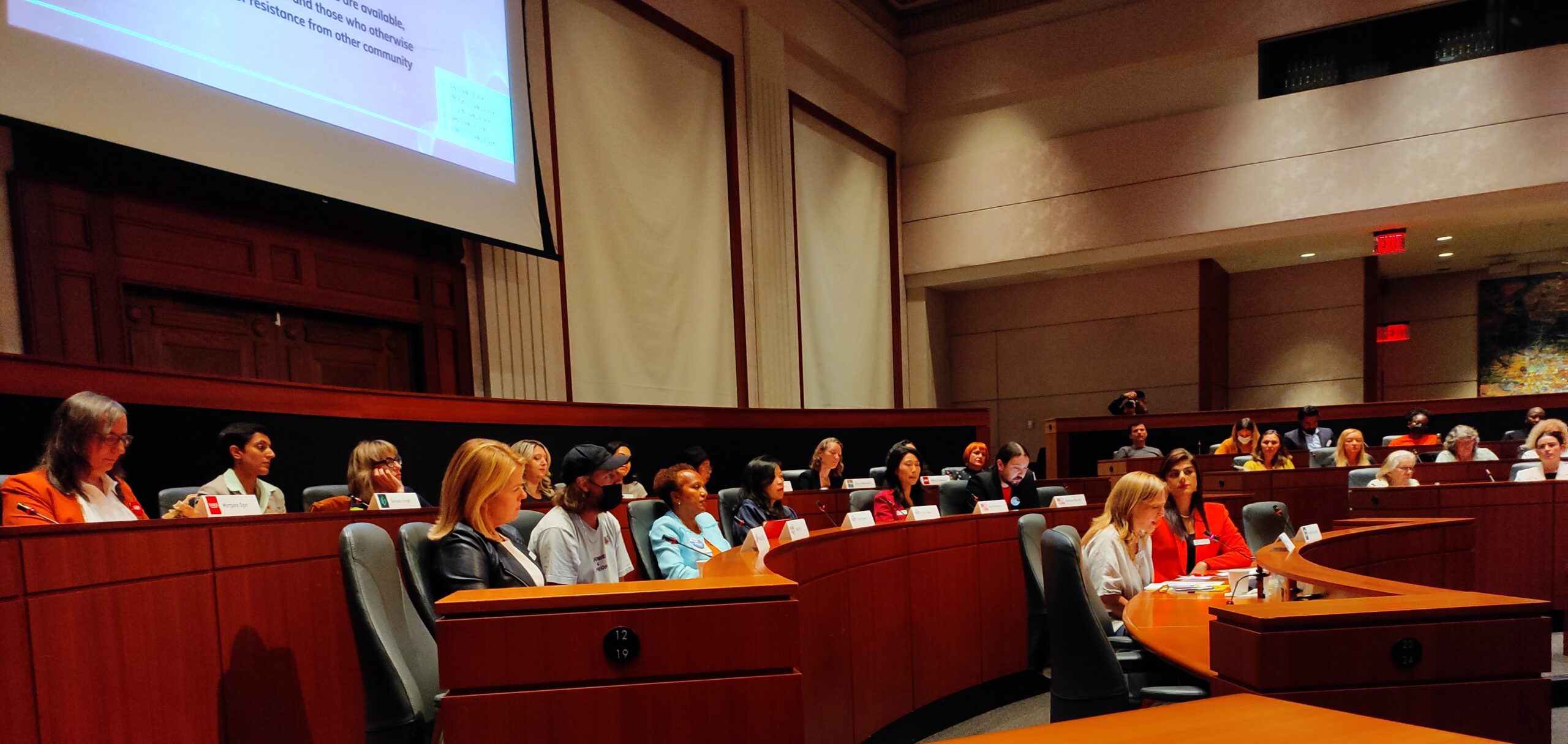 This is a photo from the SFU public square event where city council candidates are sitting at tables in front of an audience.