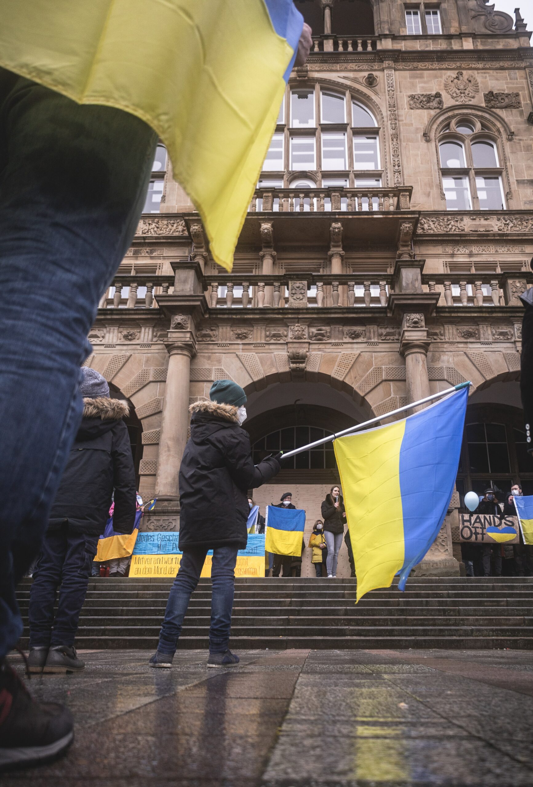 This photo is of people gathered in a group waving large Ukrainian flags.