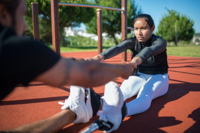 photo a woman stretching on the ground, leaning over to reach her partner