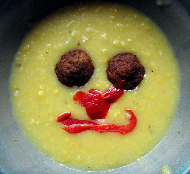 A stock photo of soup. Meatballs and radishes are arranged on its surface to look like a smiley face.