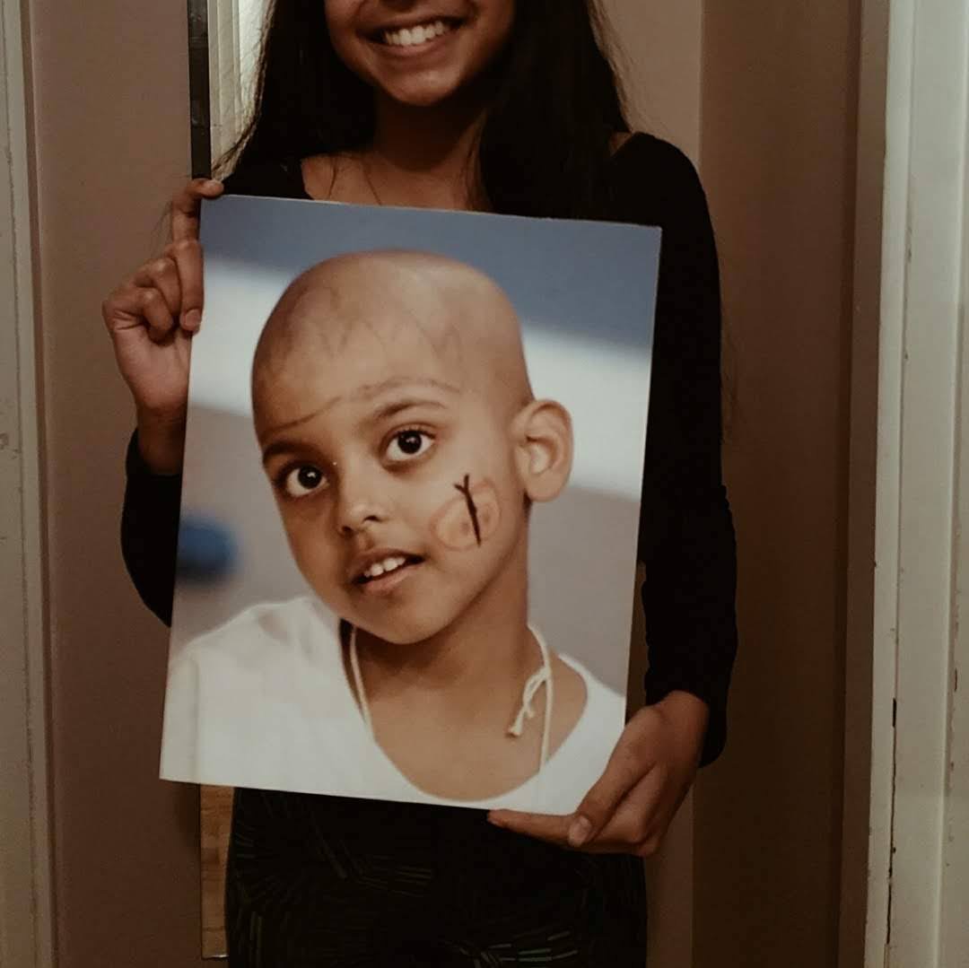 photo of Simran Sarai holding a photo of her when she was battling cancer