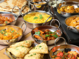 A spread of various curries, rice, and naan in metal dishes