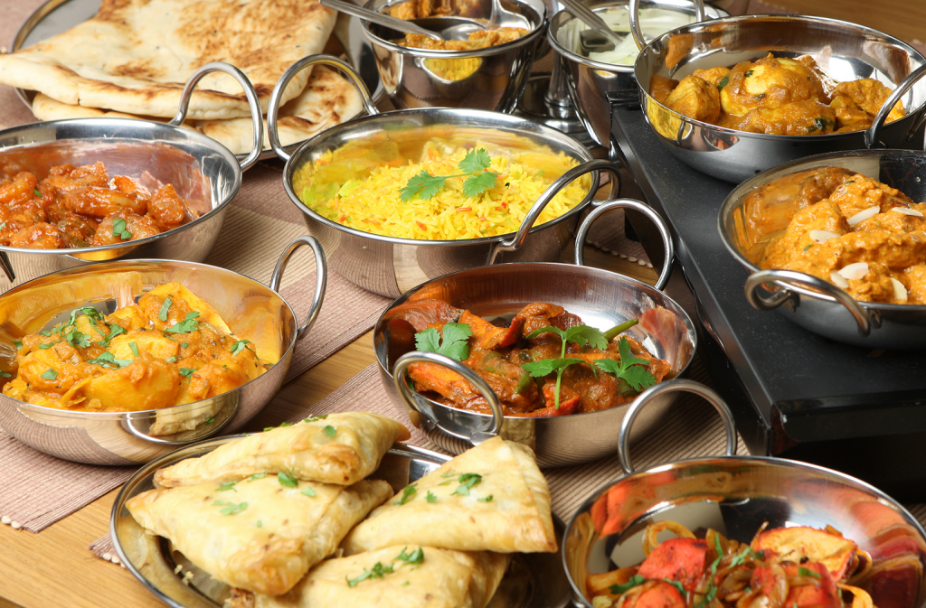 A spread of various curries, rice, and naan in metal dishes