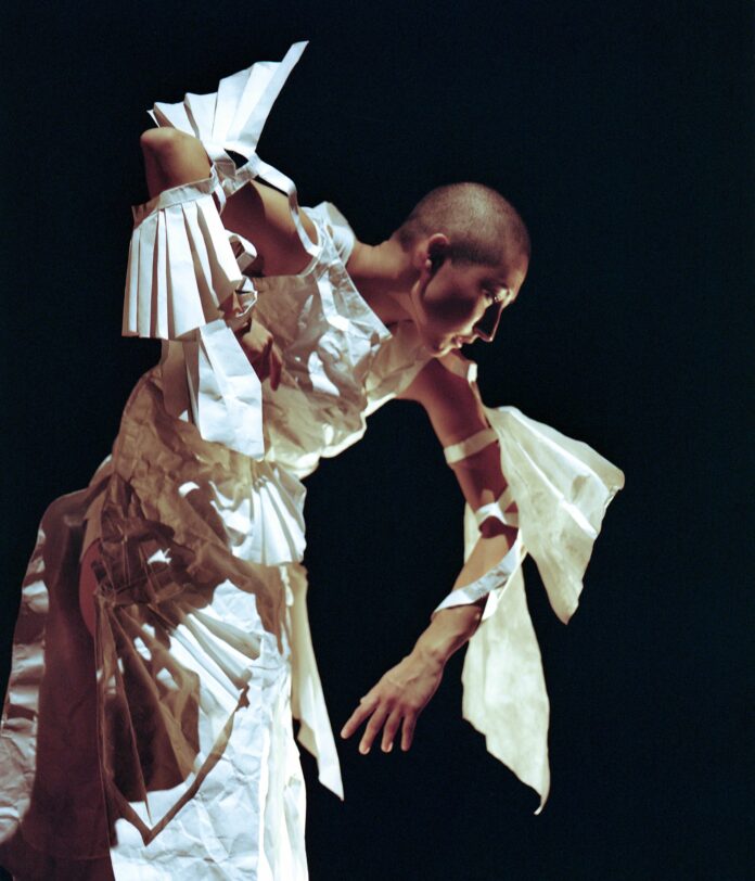 Shion Skye Carter posing in white paper garments in front of a black background