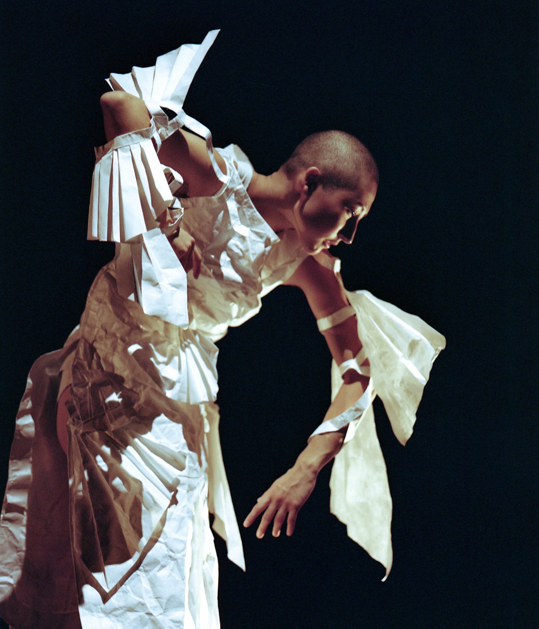Shion Skye Carter posing in white paper garments in front of a black background