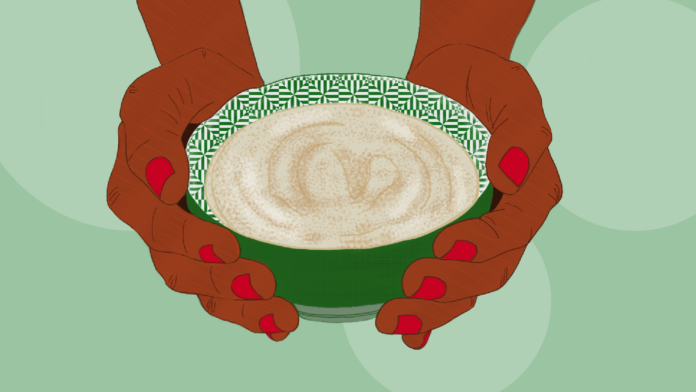 A green bowl of porridge being served by hands with red nail polish