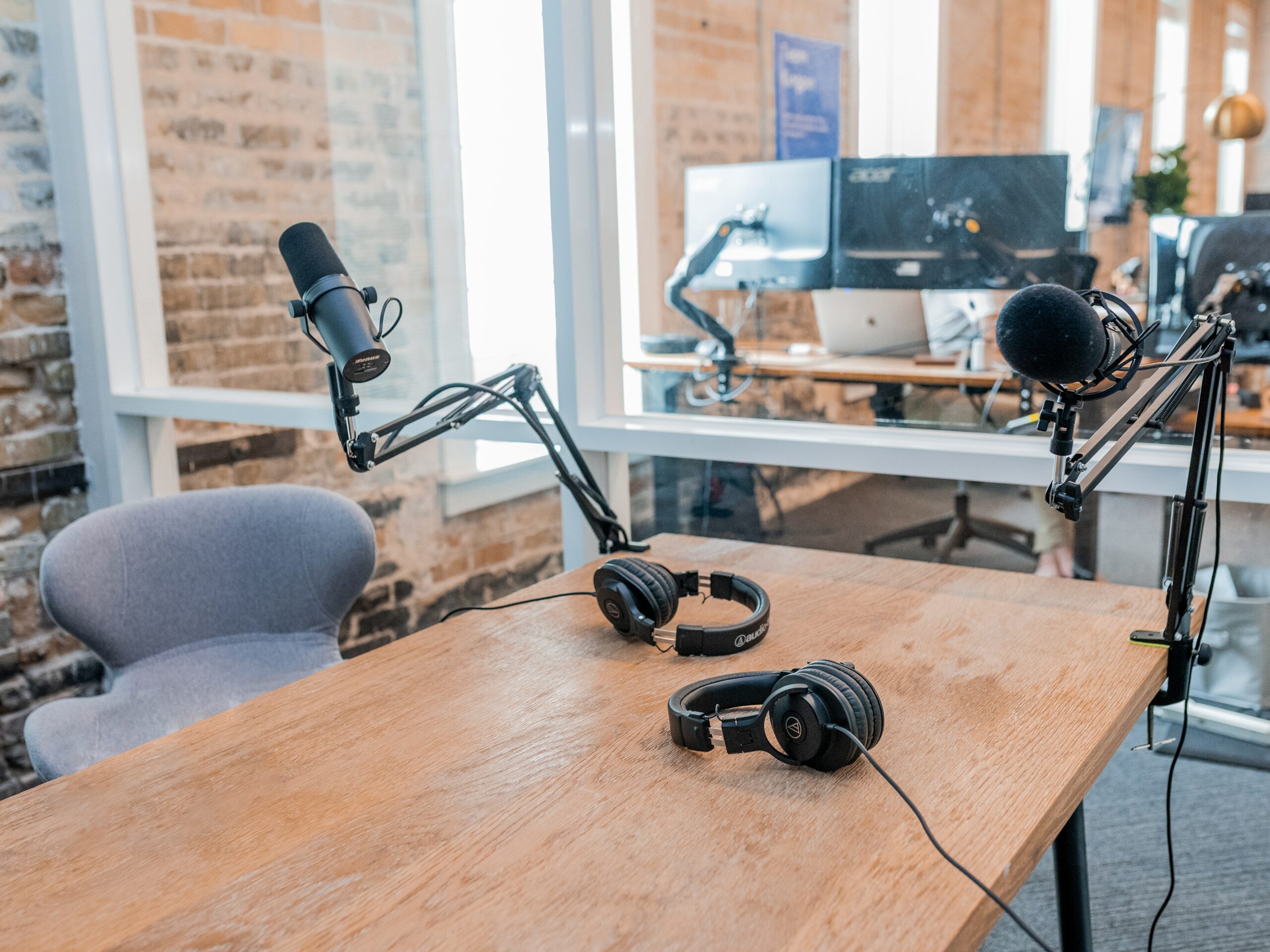 This is a photo of a podcast studio. There is recording equipment, microphones, and laptops set up around a table in a small room.