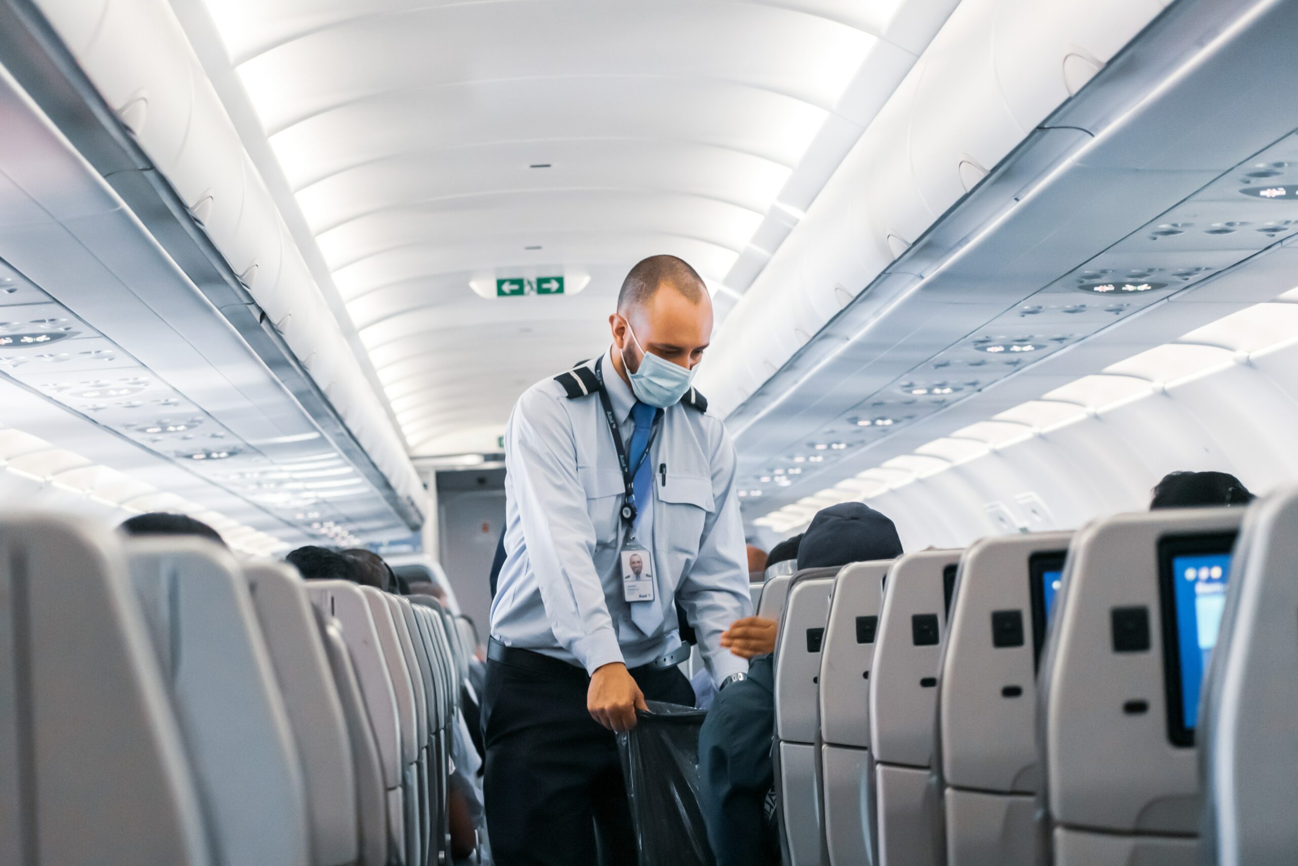 Man in a blue shirt and wearing a blue mask in an airplane