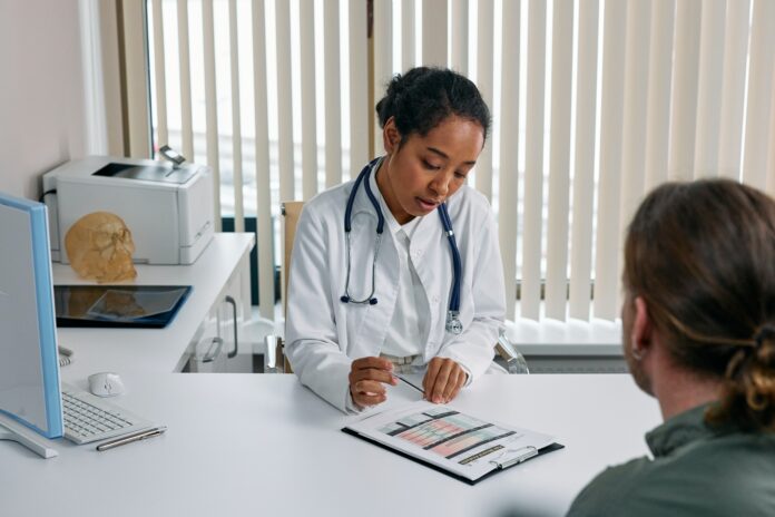 This photo is of a patient at a doctor’s office. The doctor is overlooking the paperwork.