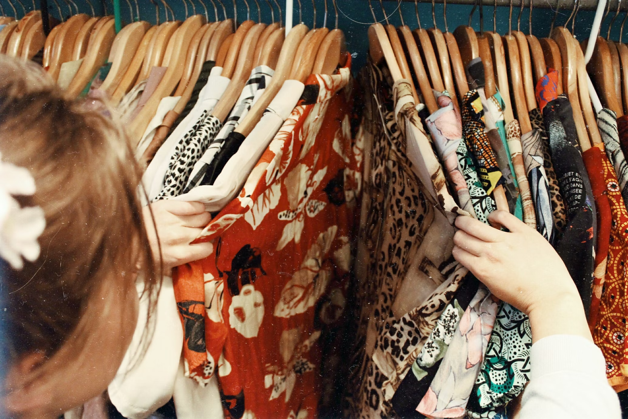 Person browsing colorful clothing on a clothing rack