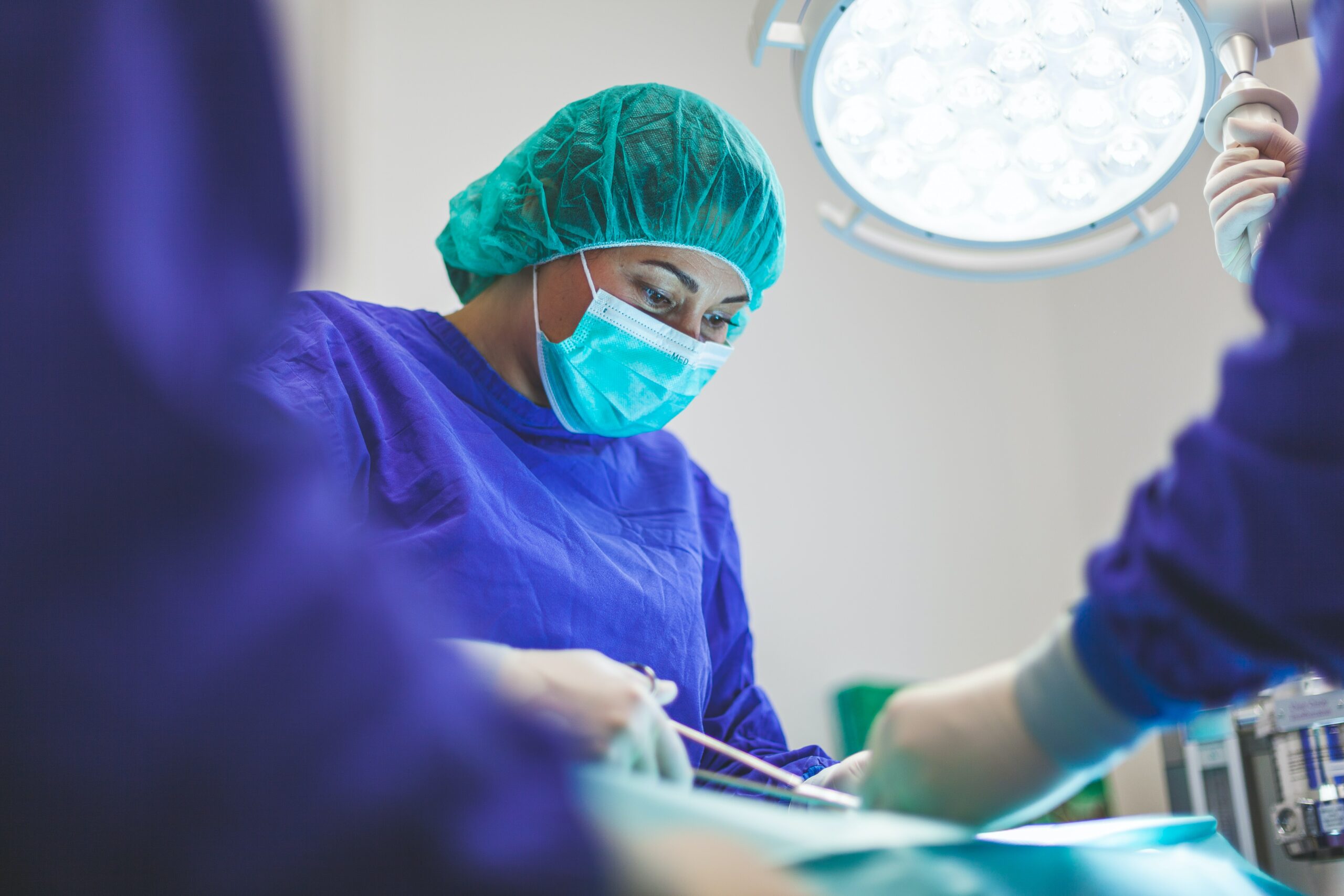 This is a photo of a woman working in a health care room. The woman appears to be doing a surgical procedure based on her clothes, but no patient is shown in the photo.