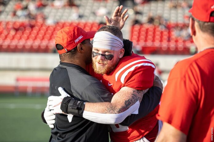 photo of head coach Mike Rigell hugging a player on the field.