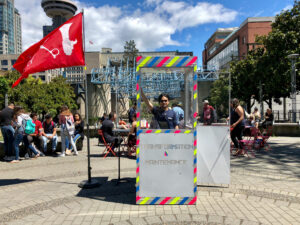 Germaine Koh and Aron Louis Cohen stand inside Home Made Home Boothy, as part of Afterlives (currency) by Koh, Cohen, and Russell Gordon, 2018.