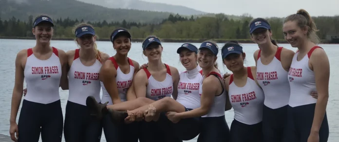 Photo of members of the SFU rowing club posing on the shore.