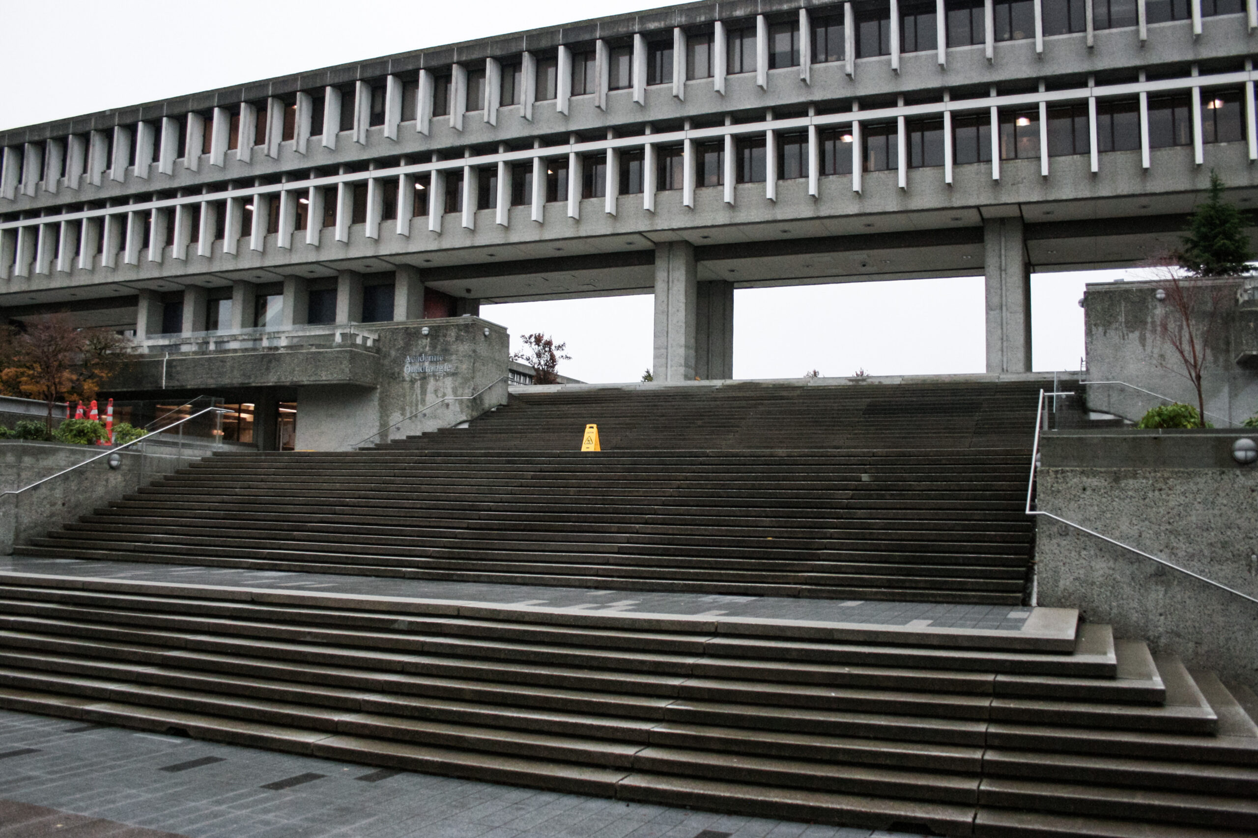 This is a photo of the SFU Burnaby campus. The outdoor staircase into the convocation mall is shown. The sky is dark and cloudy.