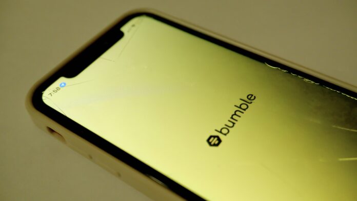 sf-buddy A photo of two students in blazers holding up phones showing the Bumble app.