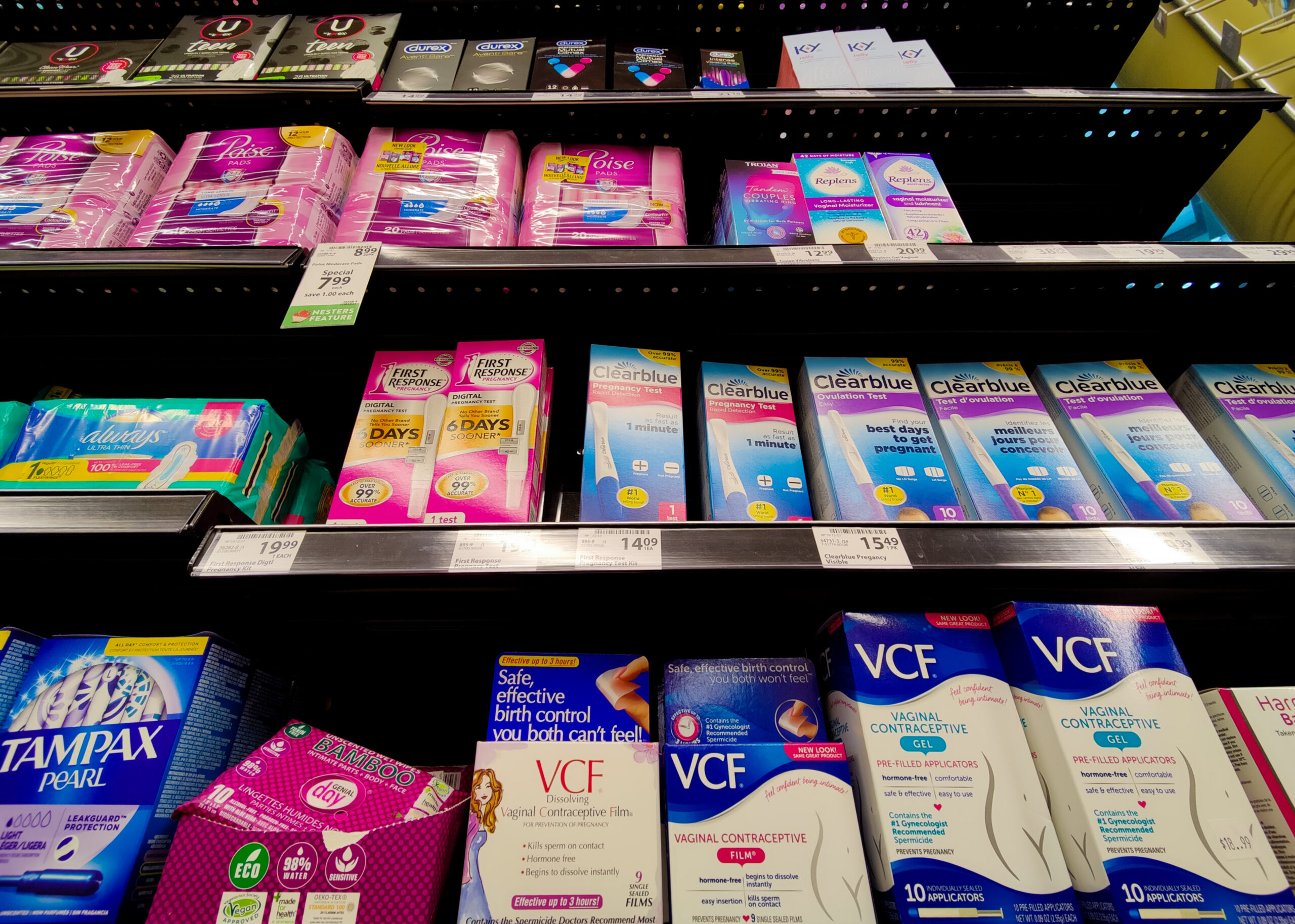 This is a photo of pregnancy test, contraceptive gel, and tampons on a store market shelf.