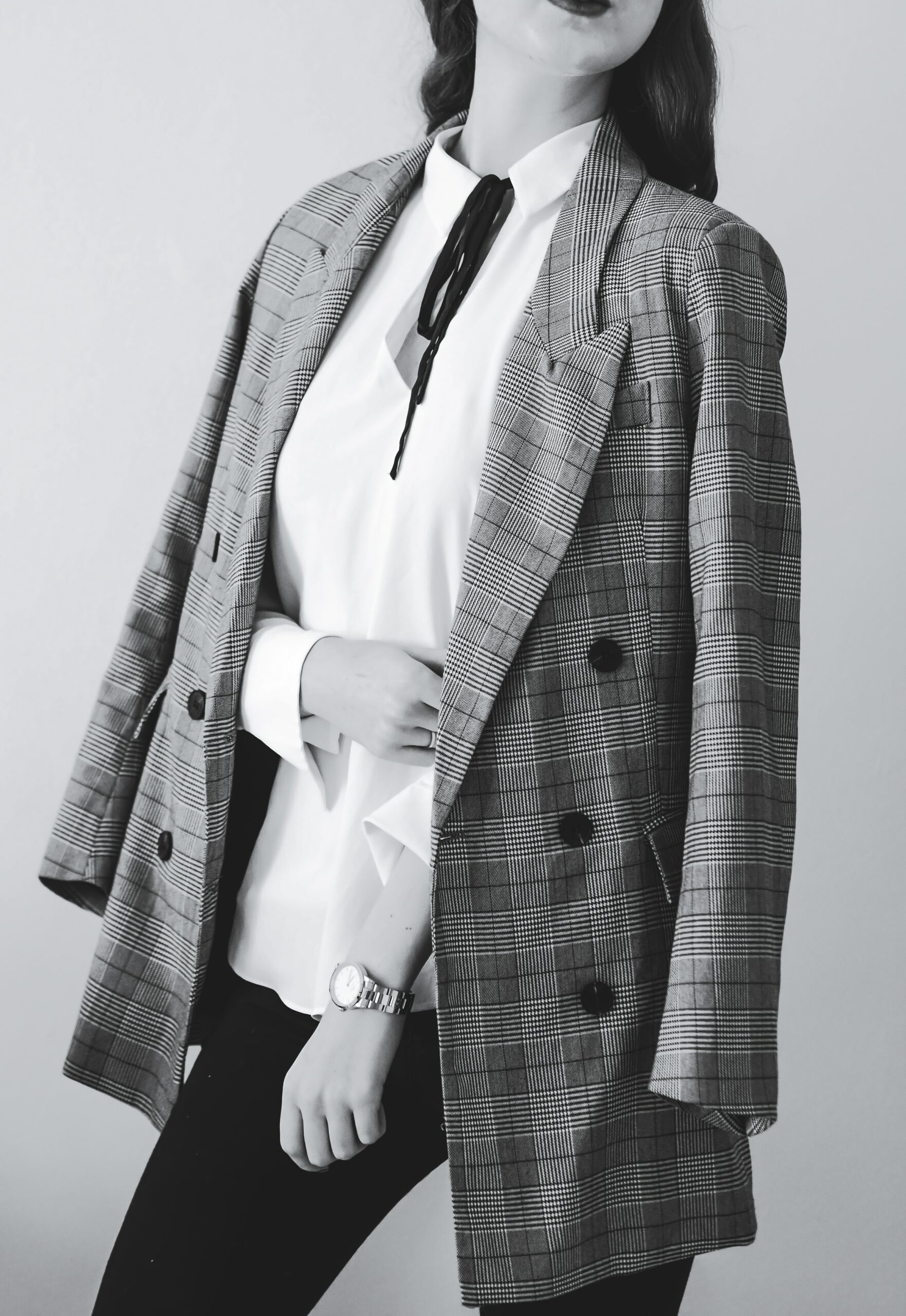 A black and white image showing the torso of a person wearing a gingham blazer over a white blouse.