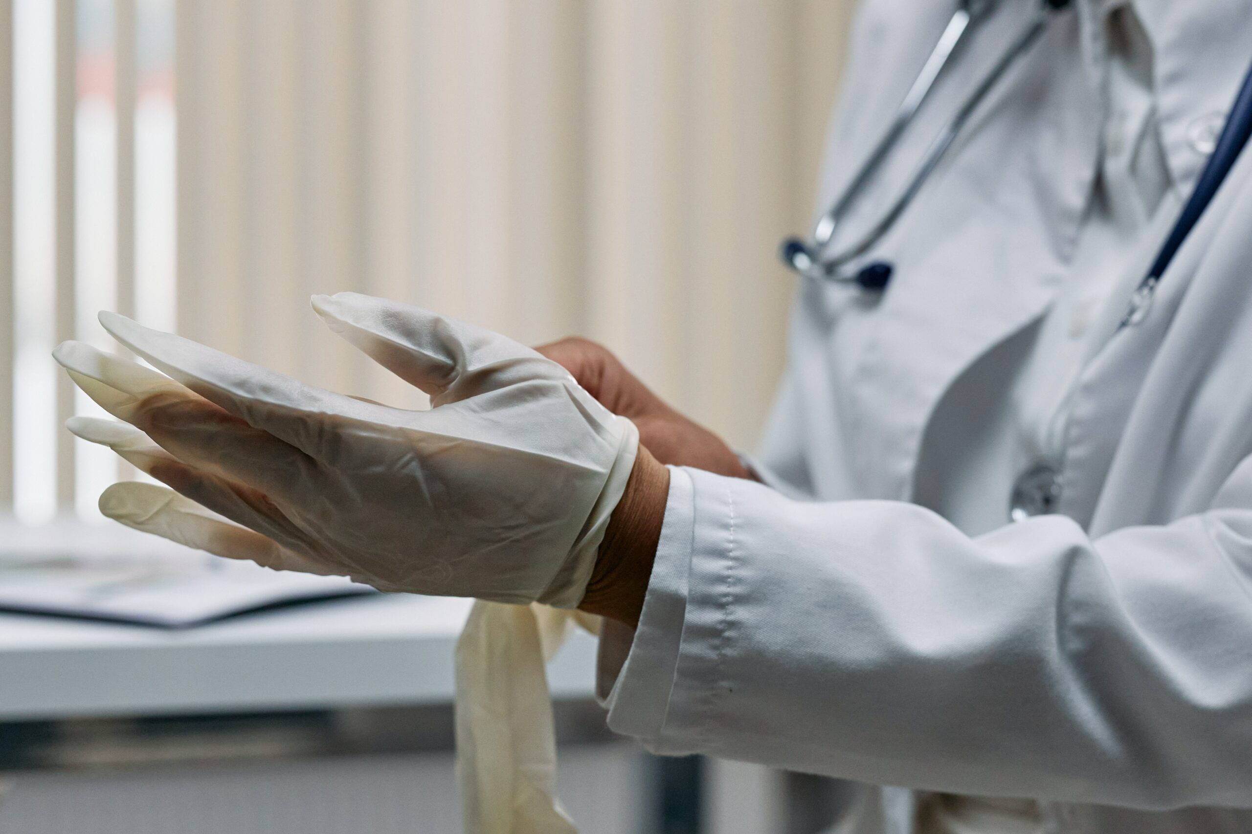 a medical professional wearing a white coat and putting on gloves