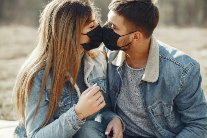 This is a photo of two people kissing each other through the face masks they are wearing.