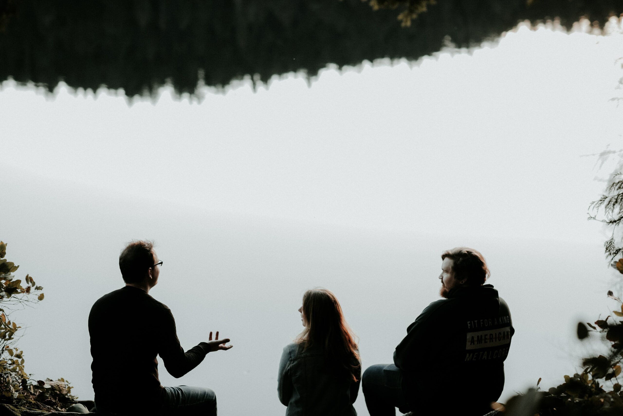 Three people talking by lake
