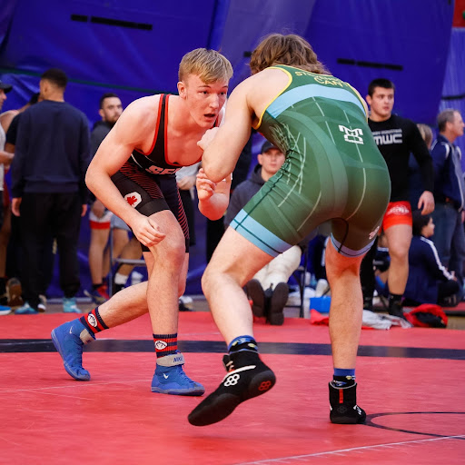 photo of SFU men’s wrestler Owen Gudmundson taking down his opponent on the mat.