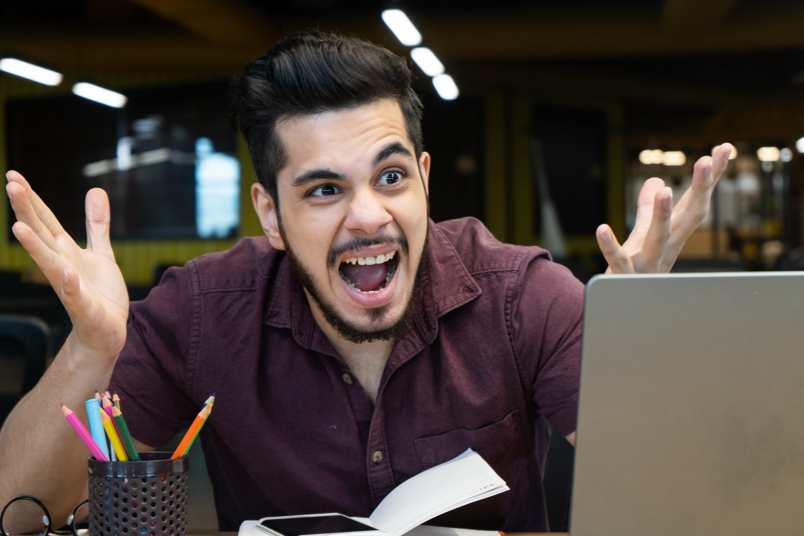 A photo of a man, looking frustrated, at his laptop.