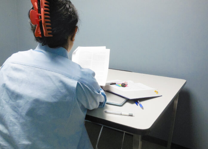 This is a photo of a student looking at their pages of homework. Their back is to the camera as they sit at a table