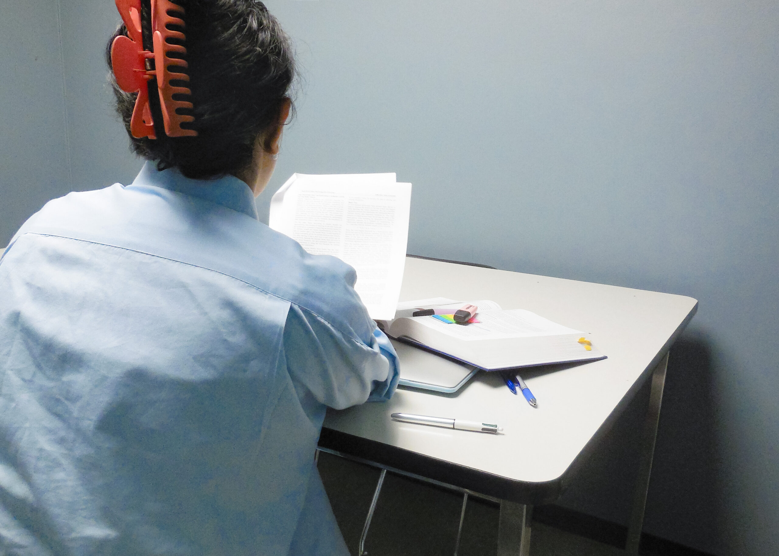 This is a photo of a student looking at their pages of homework. Their back is to the camera as they sit at a table