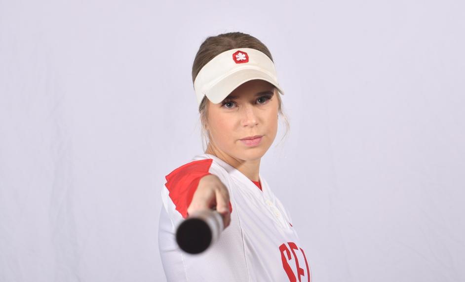 Photo of an SFU women’s softball player pointing their bat at the camera.