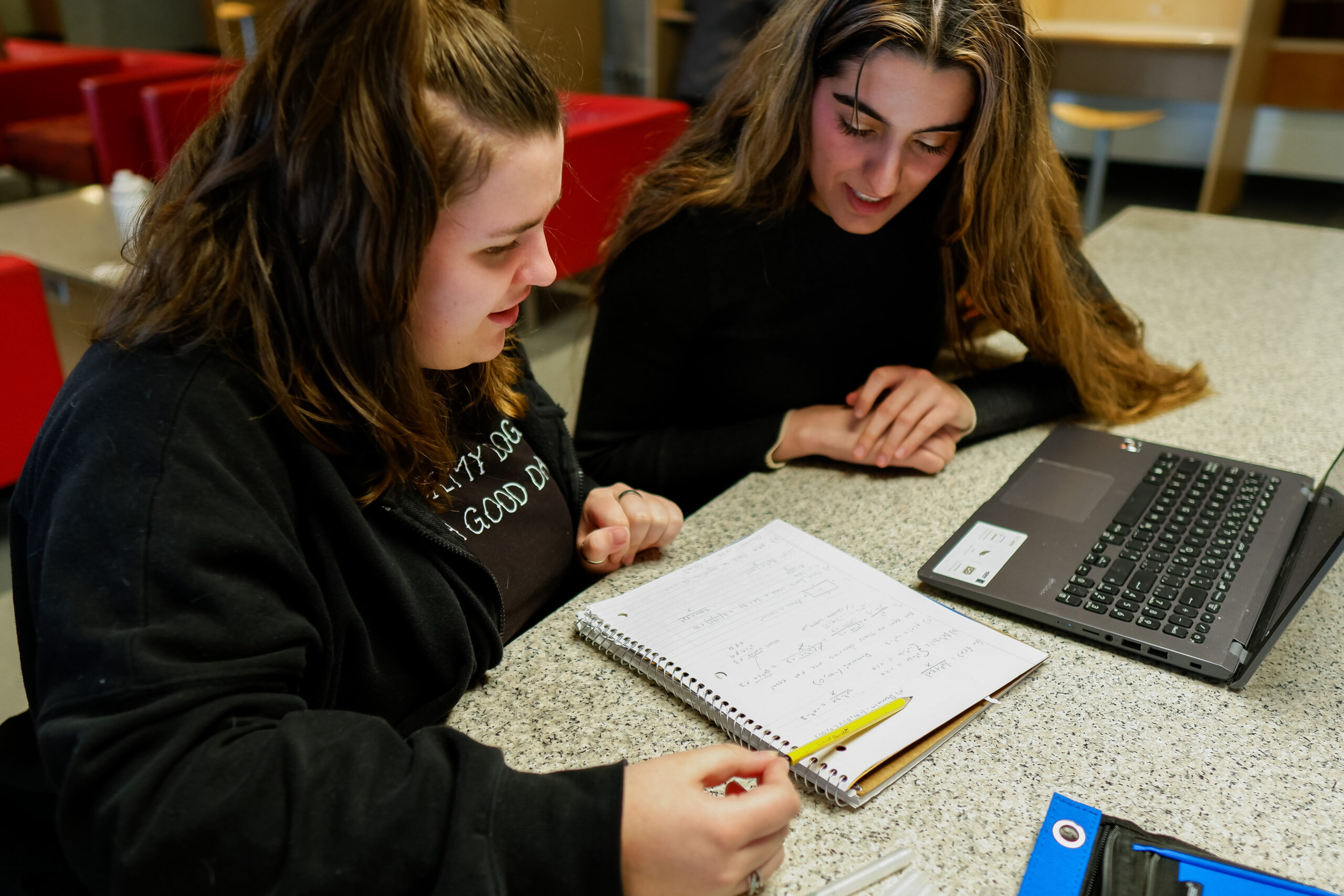 Photo of a student helping another student with homework questions.