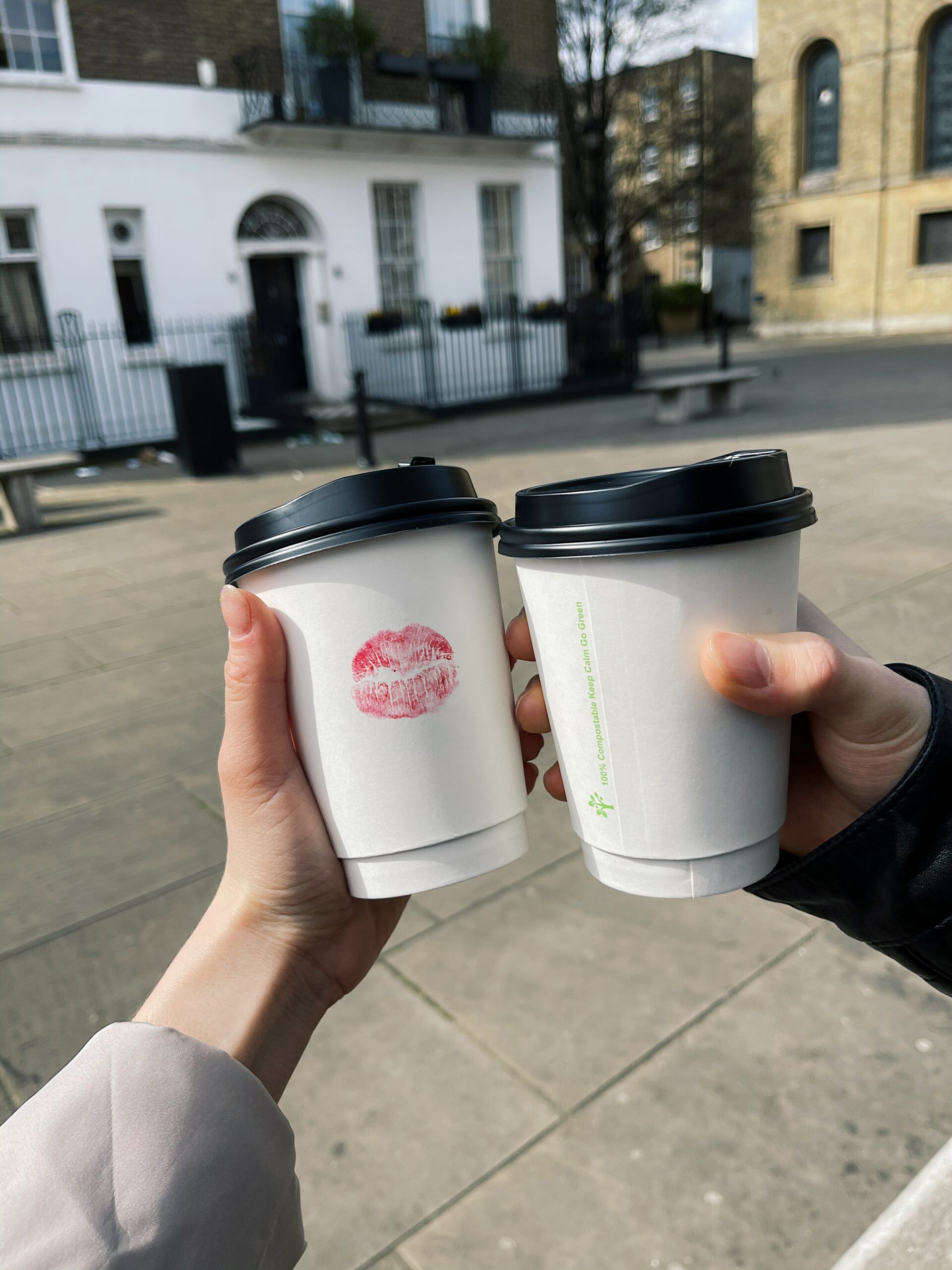 Cropped photo of couple toasting with disposable coffee cups