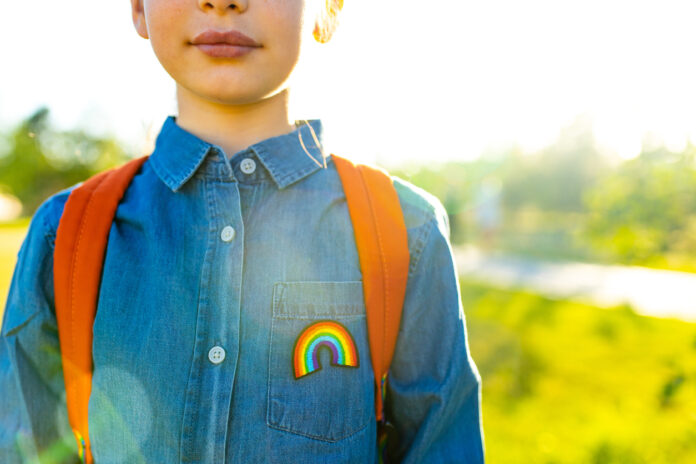 girl in denim t-shirt with rainbow symbol wear backpack in summer park outdoor.