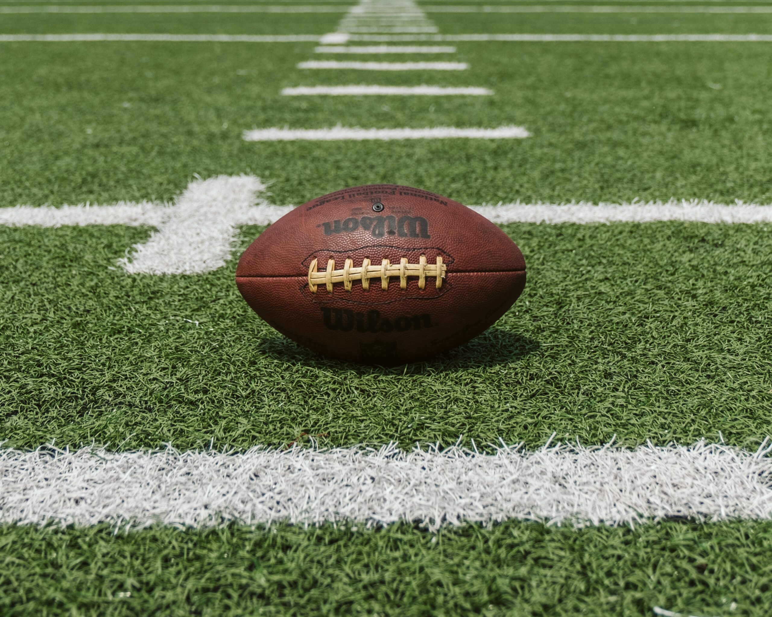 This is a photo of a football sitting in the middle of an empty football field.