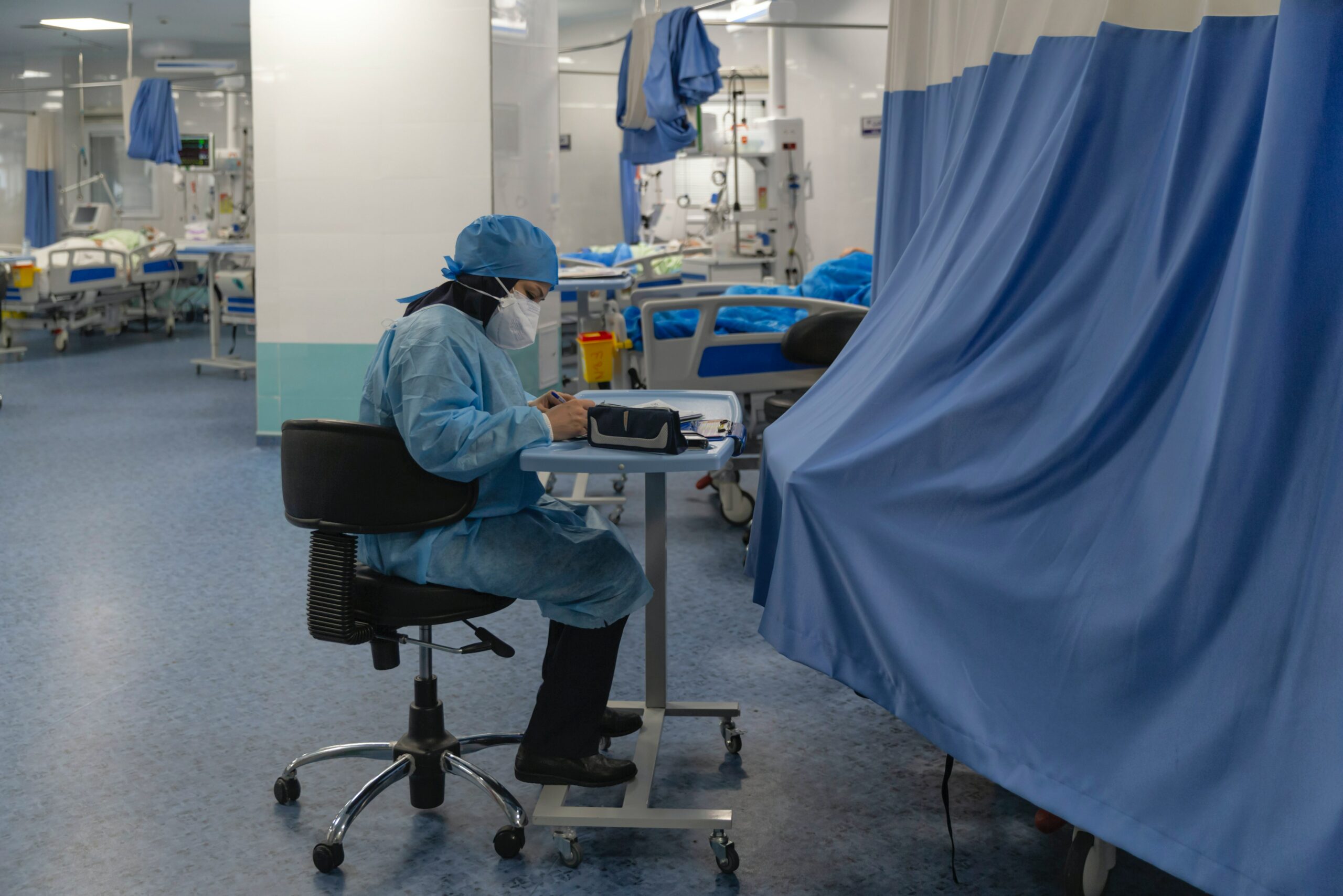 A healthcare provider sitting in a hospital, wearing a head strap N95 mask.