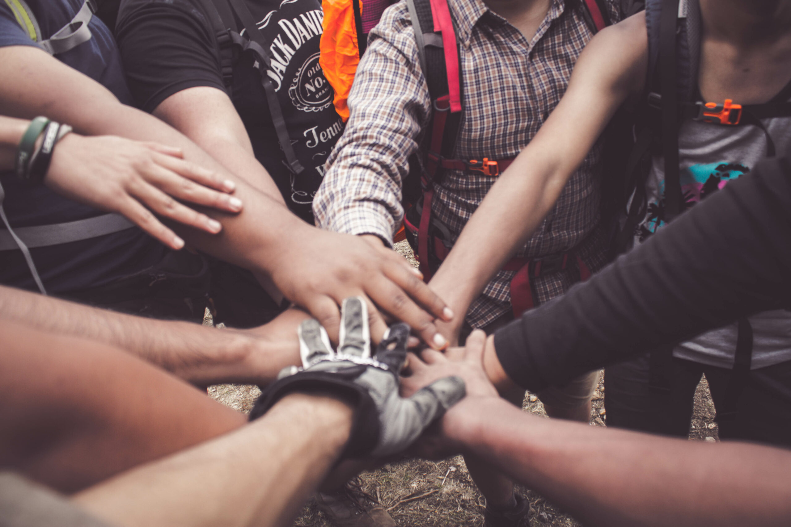 A group of people pictured around each other, hands extended toward the center to do a cheer.