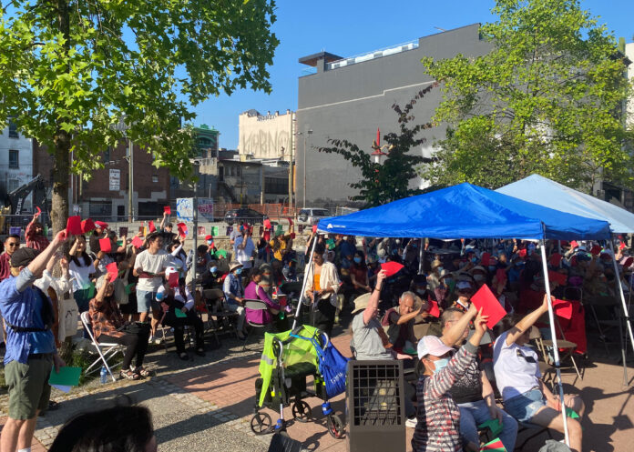 Multiple citizens are gathered, holding up signs and cards under a blue tent at 105 Keefer to rally against the Beedie development proposal.