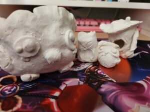 A row of sculpted owls made from white clay.