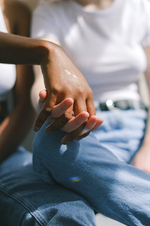 A photo of two feminine individuals holding hands.