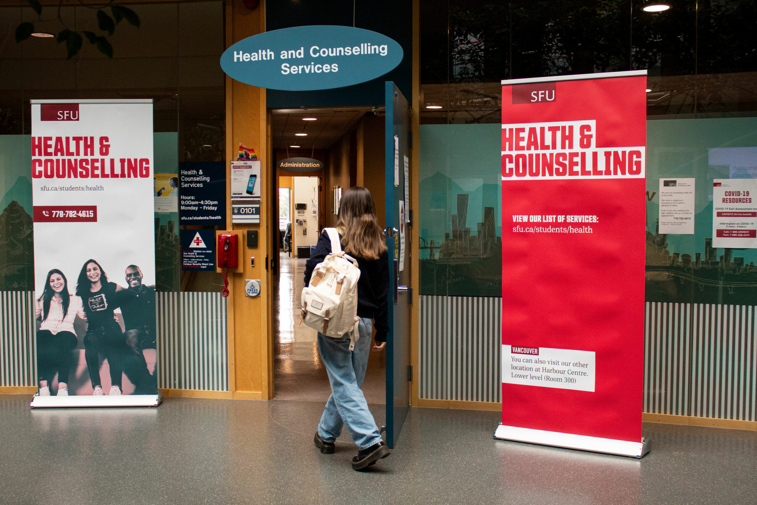 A student standing at the doors of SFU Health and Counselling