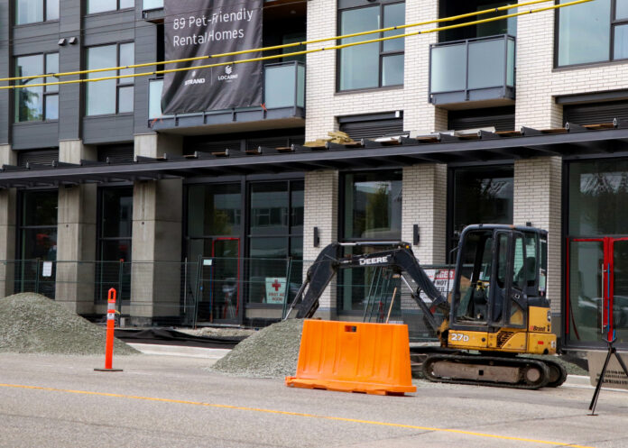 ndp-renoviction-plan a white apartment under construction with a crane in the foreground.