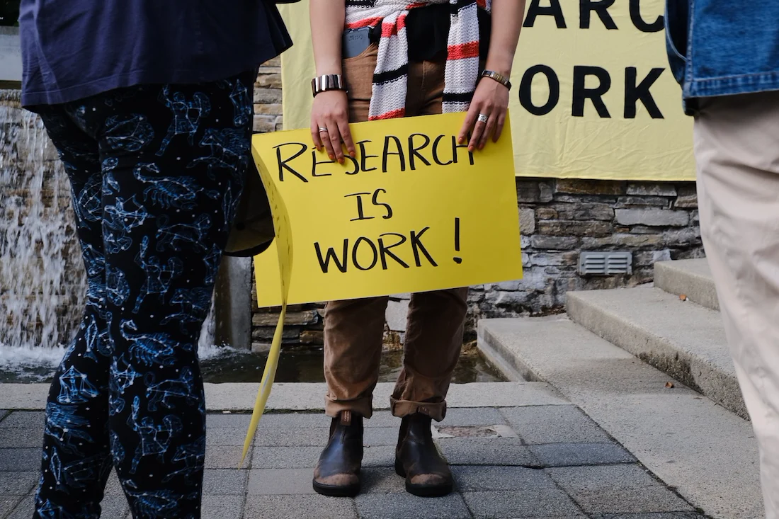 A sign reading "research is work"