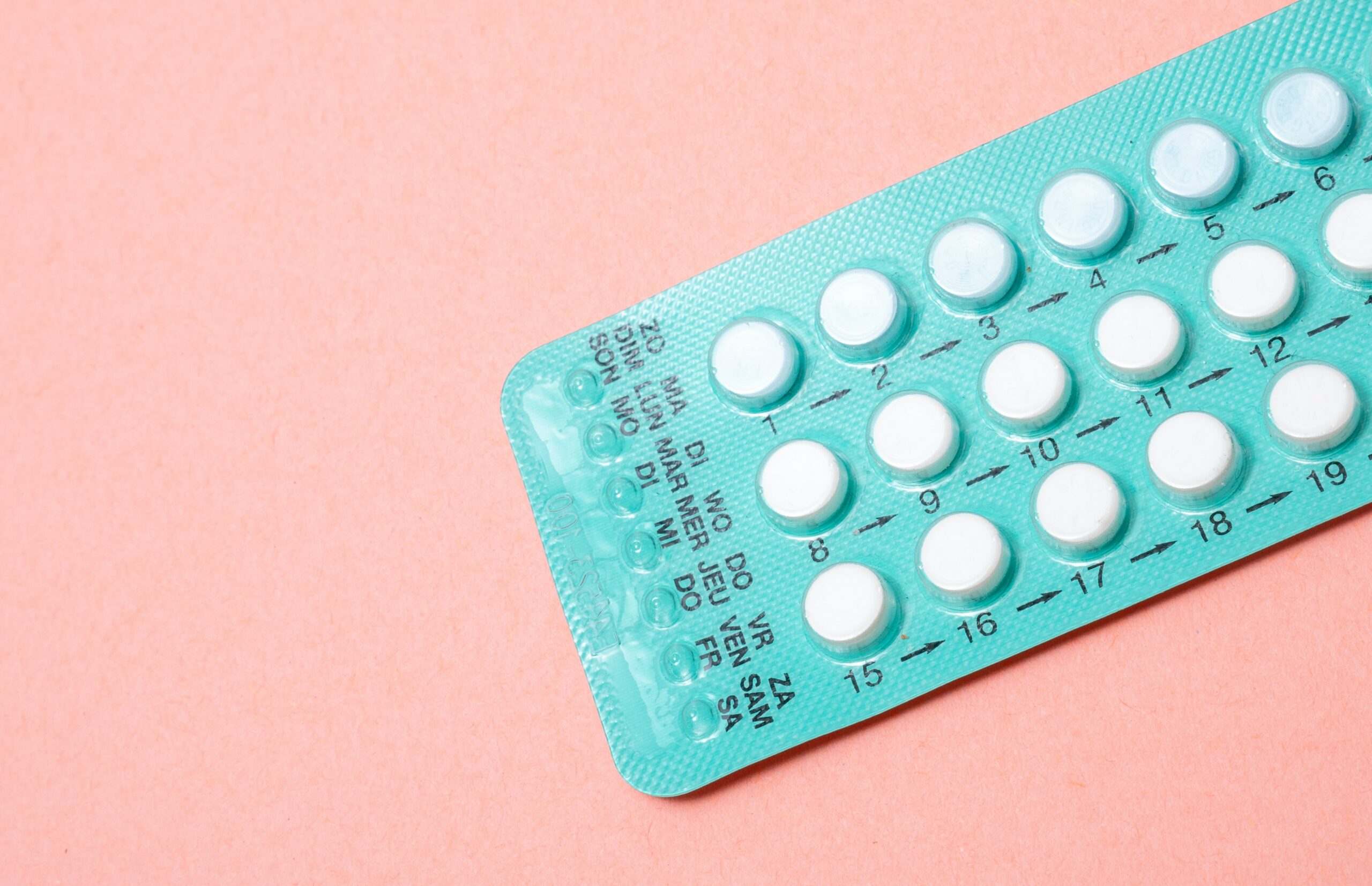 a blister pack of oral contraceptive against a pink background