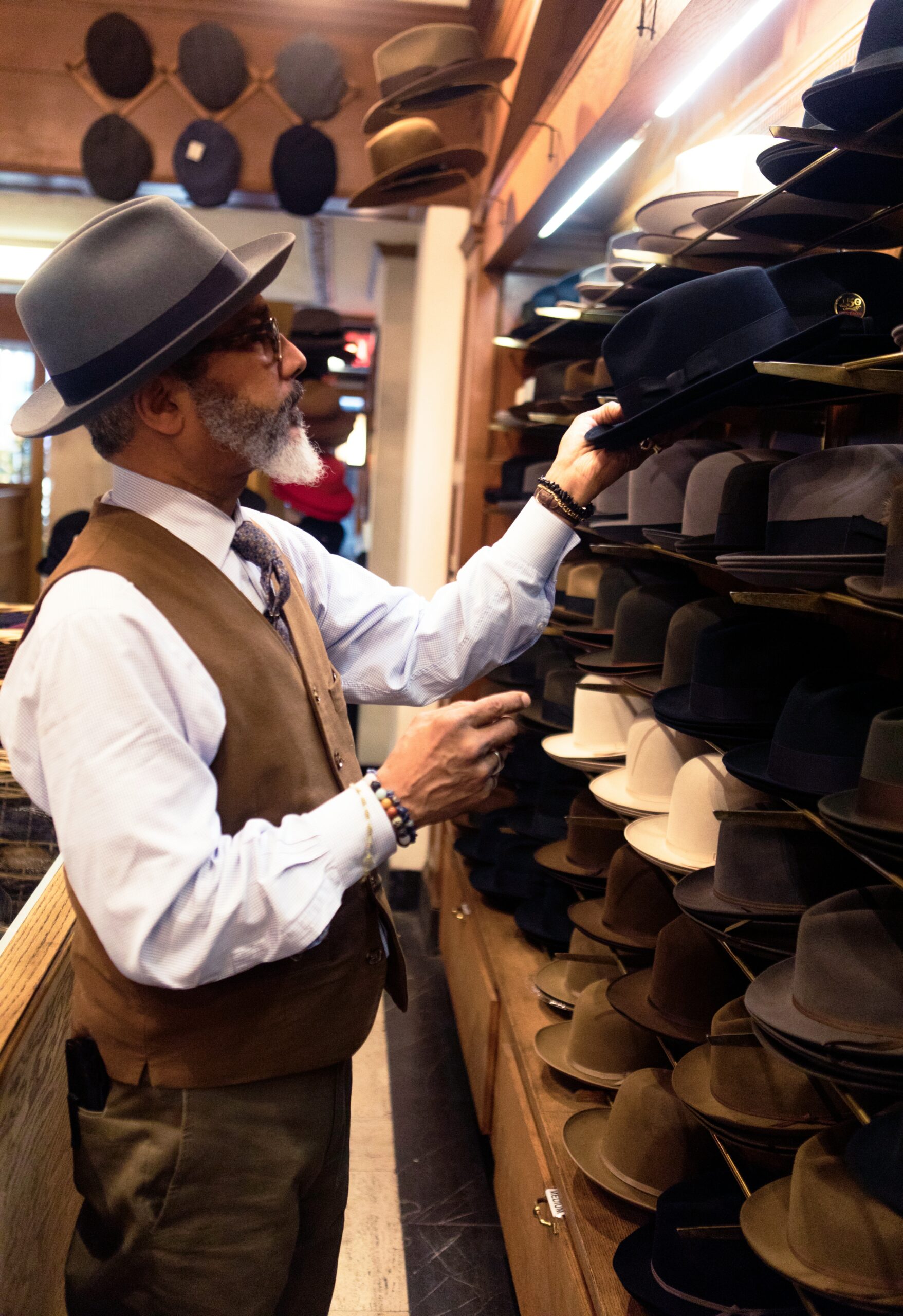 Man picking hats on a store’s shelf.