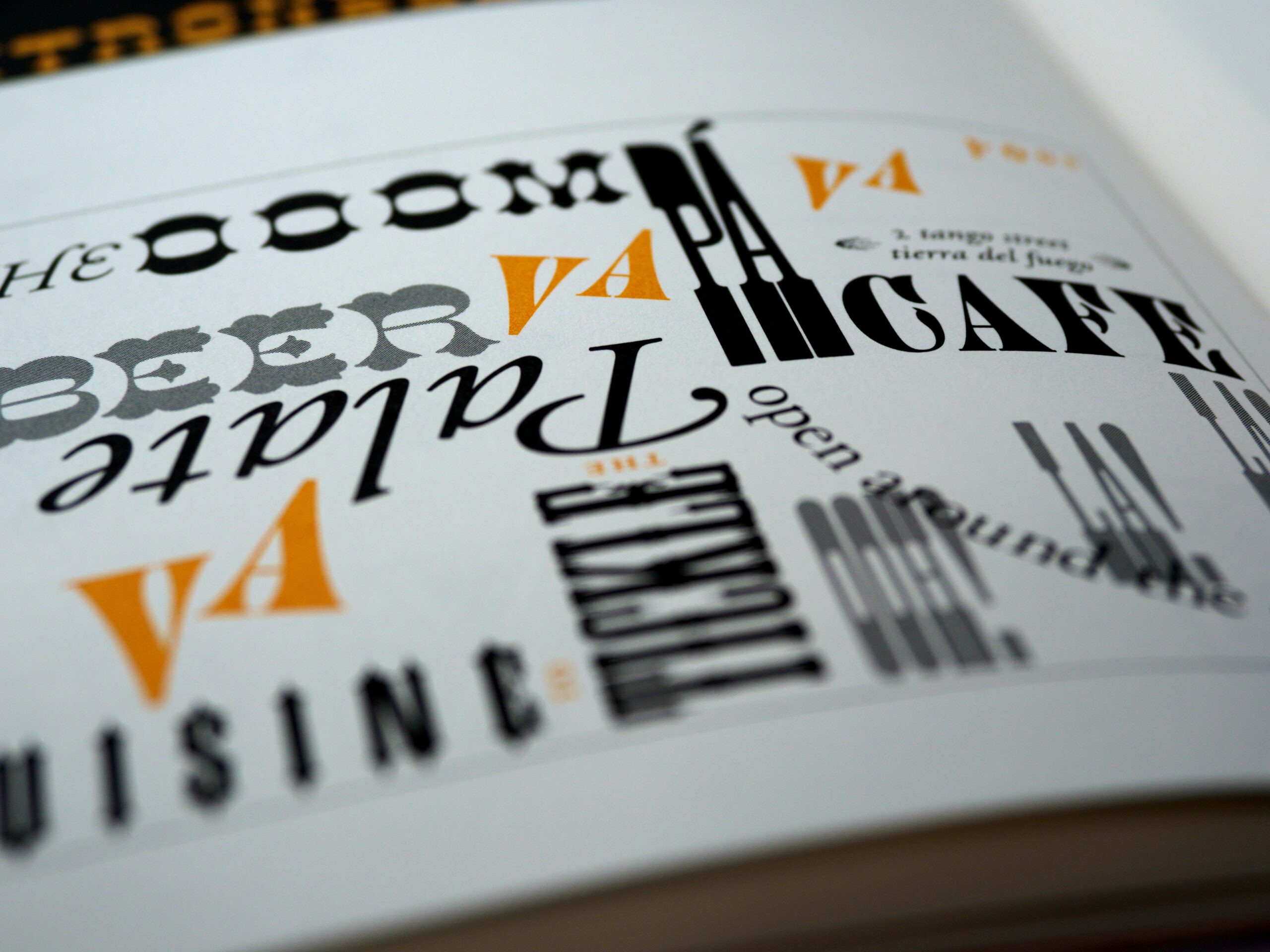 Orange, black, and grey words written on a page in all sorts of fonts.
