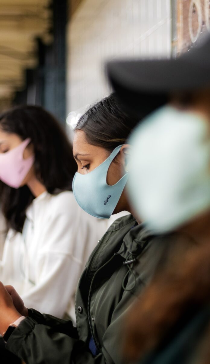 This is a photo of an individual on a bus wearing a mask. The two people next to them are also wearing masks.