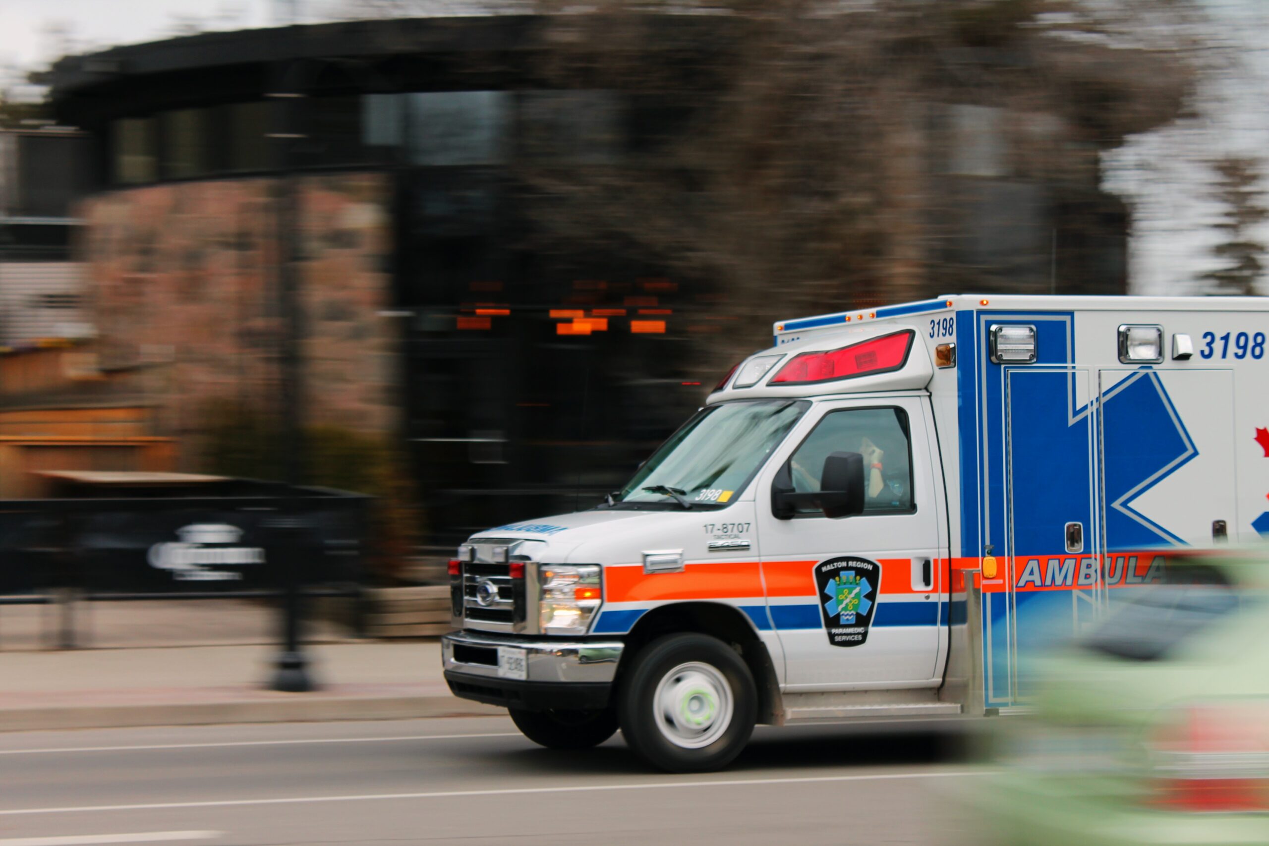 This is a photo of an ambulance, driving down the street with its emergency lights on.